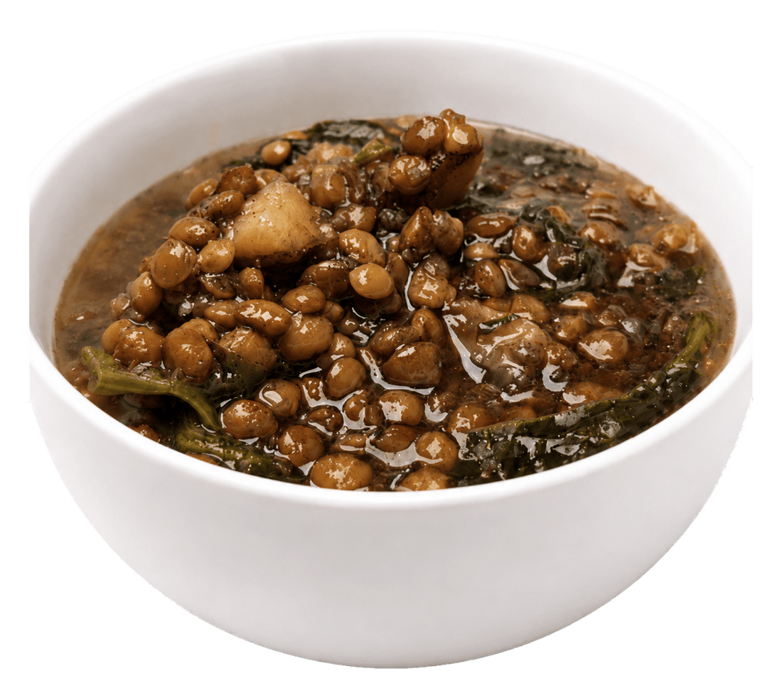 White bowl of thick lentil soup with pieces of potato and spinach.