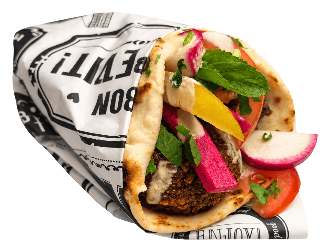 Pita wrap with falafel, pickled turnip, radish, tomato and mint in printed paper.