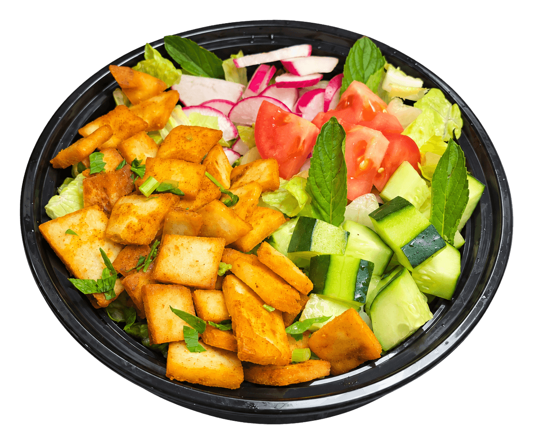 Black bowl of fattoush with crispy pita chips, tomato, cucumber, radish and mint.