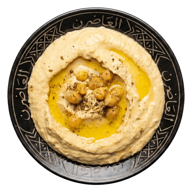Hummus swirled on a black plate with Arabic calligraphy around the rim, topped with chickpeas and olive oil.