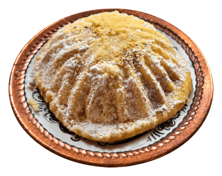 Round ma'amoul cookie dusted with powdered sugar on a decorated plate.