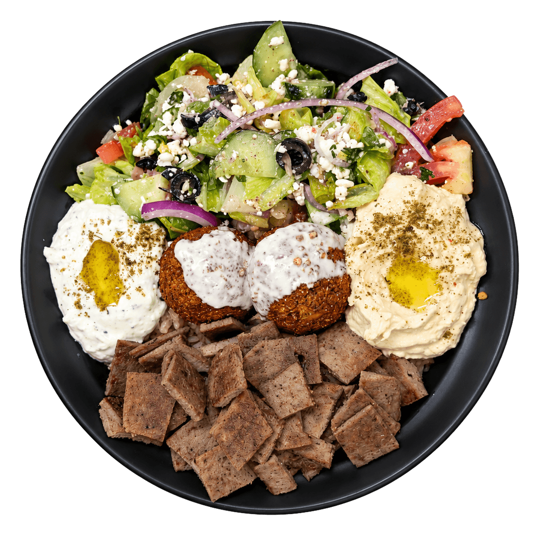 Black bowl with salad, falafel, hummus, jocoque and gyro meat, seen from above.