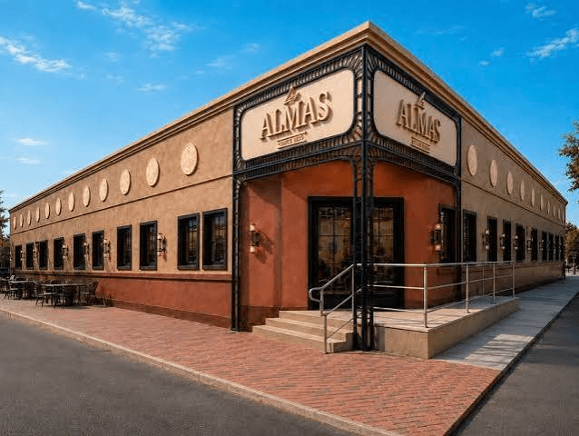 Exterior of Las Almas Food Hall in Edinburg: a corner building in stucco and brick with an iron canopy over the entrance and the venue's sign above it.
